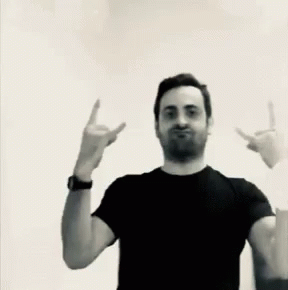 A Man In A Black Shirt Is Making A Devil Horns Sign GIF