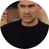 a man in a black shirt is making a funny face in a circle on a white background .