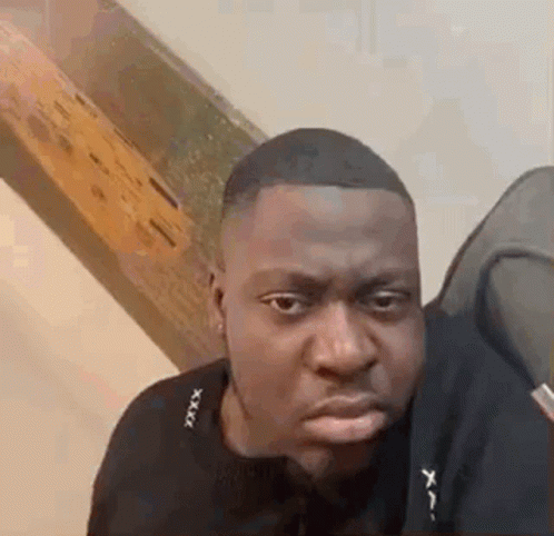 A Man In A Black Shirt Is Making A Funny Face While Looking At The Camera . GIF
