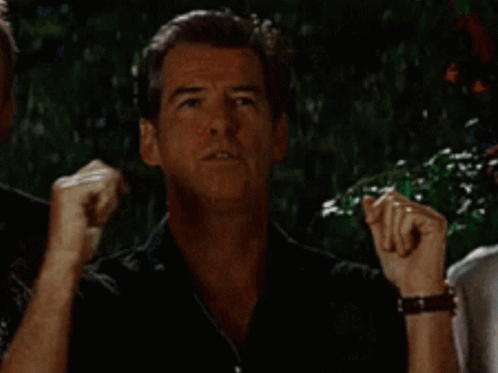 A Man In A Black Shirt Is Making A Funny Face While Standing Next To Another Man . GIF