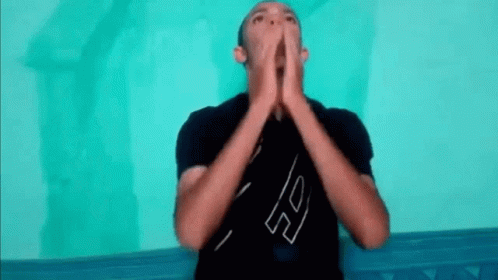 A Man In A Black Shirt Is Making A Funny Face With His Hands Together . GIF