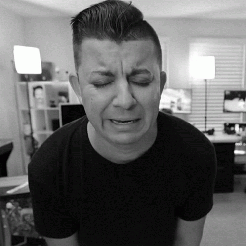A Man In A Black Shirt Is Making A Sad Face With His Eyes Closed GIF