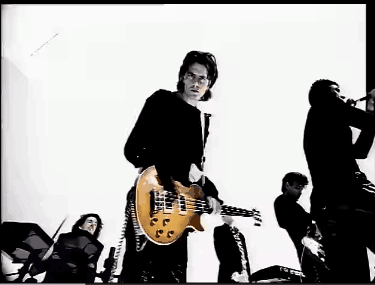 A Man In A Black Shirt Is Playing A Guitar In A Black And White Photo GIF