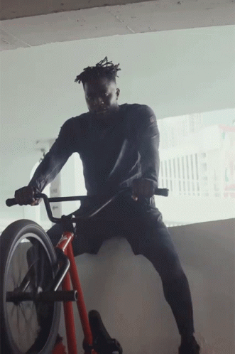 A Man In A Black Shirt Is Riding A Bike GIF