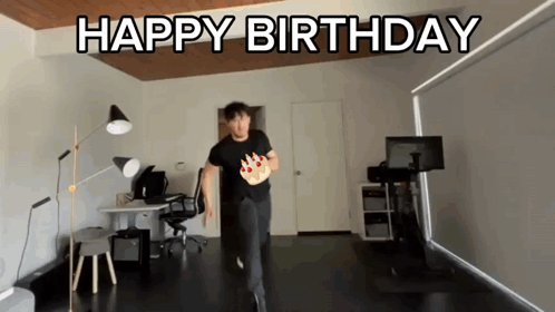 a man in a black shirt is running with a birthday cake in his hand and the words happy birthday behind him