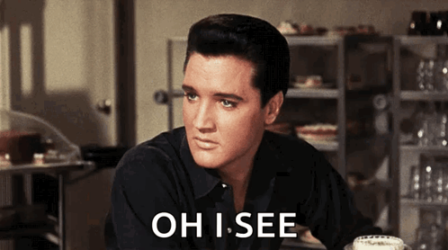 A Man In A Black Shirt Is Sitting At A Table With The Words Oh I See Above Him GIF