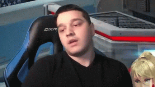 A Man In A Black Shirt Is Sitting In A Blue Dxr Chair GIF