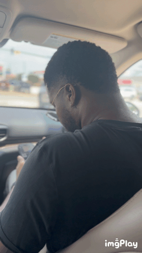 Man In Black Shirt Sitting In Car Looking At Phone GIF
