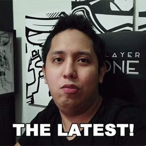 A Man In A Black Shirt Is Sitting In Front Of A Sign That Says " The Latest " GIF