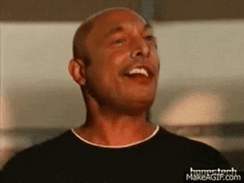 A Man In A Black Shirt Is Smiling And Looking Up At The Sky GIF