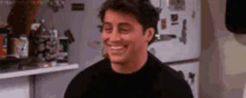 A Man In A Black Shirt Is Smiling In A Kitchen . GIF