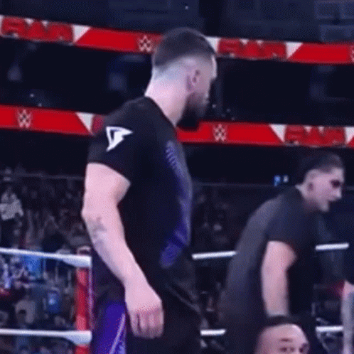 A Man In A Black Shirt Is Standing In A Boxing Ring With Another Man . GIF