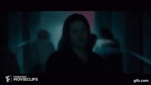 A Man In A Black Shirt Is Standing In A Dark Room In Front Of A Crowd . GIF