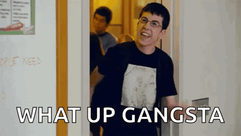 A Man In A Black Shirt Is Standing In A Doorway With The Words `` What Up Gangsta '' Written On The Bottom . GIF
