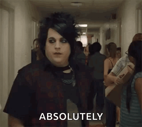A Man In A Black Shirt Is Standing In A Hallway With A Crowd Of People And Says `` Absolutely '' . GIF