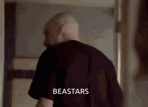 A Man In A Black Shirt Is Standing In A Hallway With The Word Beastars Written On The Bottom Of The Image . GIF