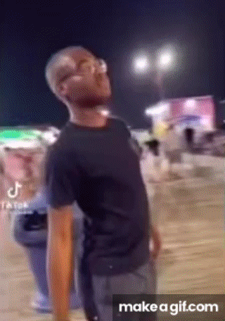 a man in a black shirt is standing in front of a crowd of people at night .