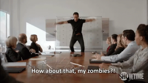 A Man In A Black Shirt Is Standing In Front Of A Group Of People And Says How About That My Zombies GIF