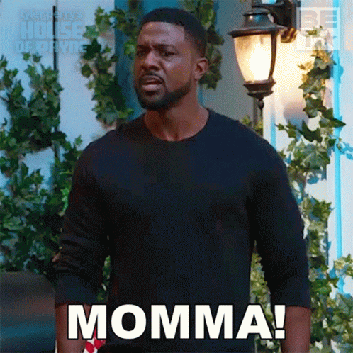 A Man In A Black Shirt Is Standing In Front Of A Street Light And Says Momma . GIF