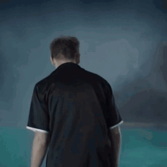 A Man In A Black Shirt Is Standing In Front Of A Swimming Pool . GIF