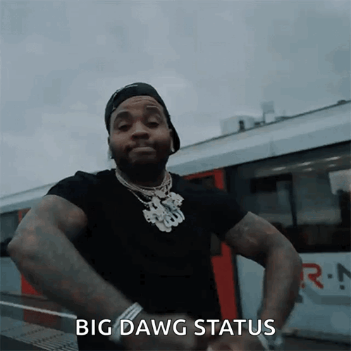 A Man In A Black Shirt Is Standing In Front Of A Train With His Hands On His Hips And Says Big Dawg Status GIF