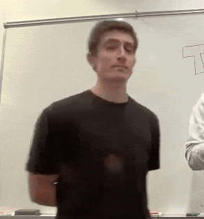 A Man In A Black Shirt Is Standing In Front Of A White Board With The Letter T Drawn On It GIF