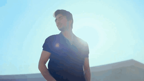 A Man In A Black Shirt Is Standing In The Sunlight GIF