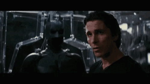 A Man In A Black Shirt Is Standing Next To A Man In A Black Suit . GIF