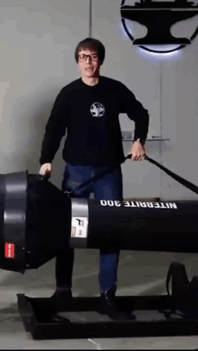 A Man In A Black Shirt Is Standing Next To A Nitebrite 300 GIF