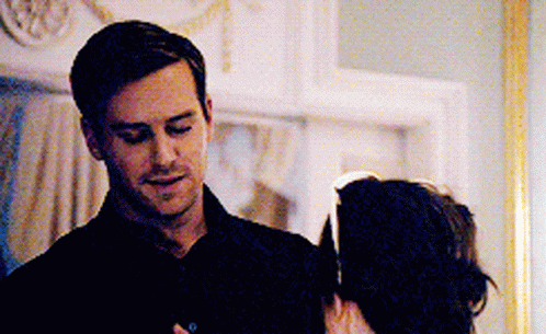 A Man In A Black Shirt Is Standing Next To A Woman In A Dark Room . GIF