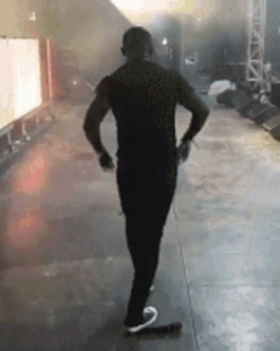 A Man In A Black Shirt Is Standing On A Stage . GIF
