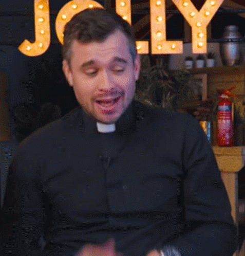 A Man In A Black Shirt Is Talking In Front Of A Sign That Says Jolly GIF