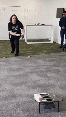 A Man In A Black Shirt Is Throwing A Frisbee In A Room GIF
