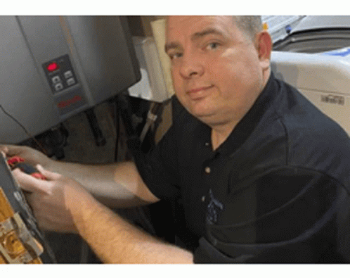 A Man In A Black Shirt Is Working On A Washer And Dryer . GIF