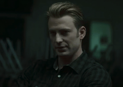 A Man In A Black Shirt Looks At The Camera With His Arms Crossed GIF