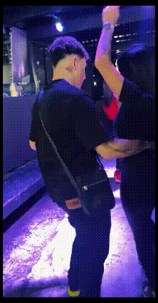 A Man In A Black Shirt Stands In A Dark Room GIF