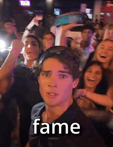 a man in a black shirt stands in front of a crowd with the word fame written on his face