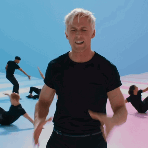 A Man In A Black Shirt Stands In Front Of A Group Of People GIF