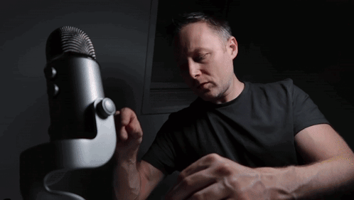 A Man In A Black Shirt Stands In Front Of A Microphone With A Bbc Logo In The Background GIF