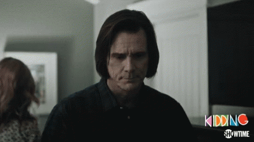 A Man In A Black Shirt Stands In Front Of A Sign That Says Kidding GIF