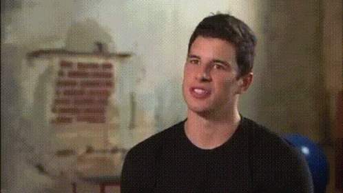 A Man In A Black Shirt Stands In Front Of A Wall With A Painting On It GIF