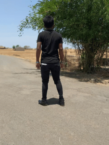 A Man In A Black Shirt Stands On The Side Of The Road GIF