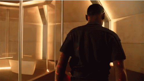 A Man In A Black Shirt Walks Through A Room GIF