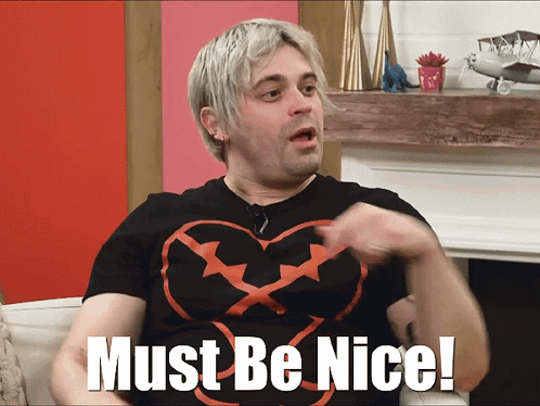 A Man In A Black Shirt With A Heart On It Says Must Be Nice GIF