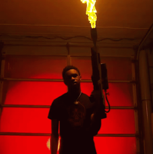 a man in a black shirt with a skull on it holds a flamethrower