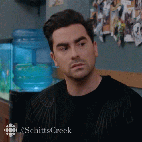A Man In A Black Shirt With #Schitts Creek On The Bottom GIF