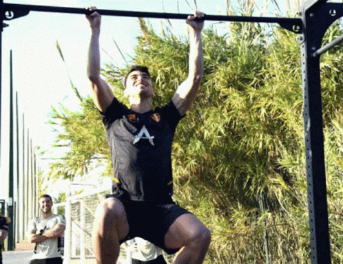 A Man In A Black Shirt With The Letter A On It Is Doing Pull Ups GIF