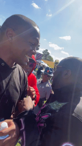A Man In A Black Shirt With The Letter O On It Talks To Another Man GIF