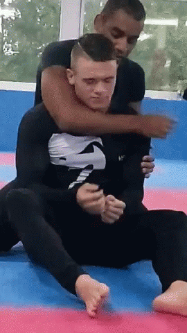 A Man In A Black Shirt With The Letter S On It Is Wrestling Another Man GIF
