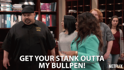 A Man In A Black Shirt With The Letter W On It Stands In Front Of A Group Of People GIF